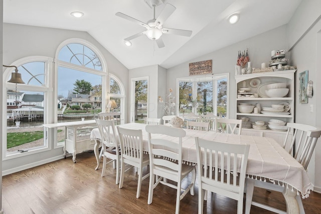 dining area with ceiling fan, wood-type flooring, and vaulted ceiling