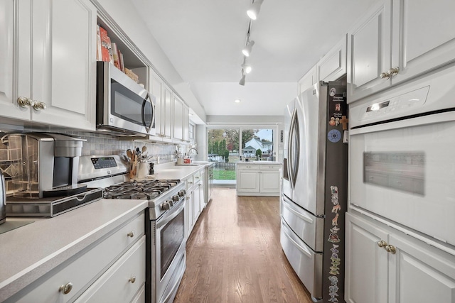 kitchen with white cabinetry, sink, backsplash, light hardwood / wood-style floors, and appliances with stainless steel finishes