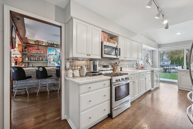 kitchen featuring white cabinets, decorative backsplash, hardwood / wood-style flooring, and appliances with stainless steel finishes