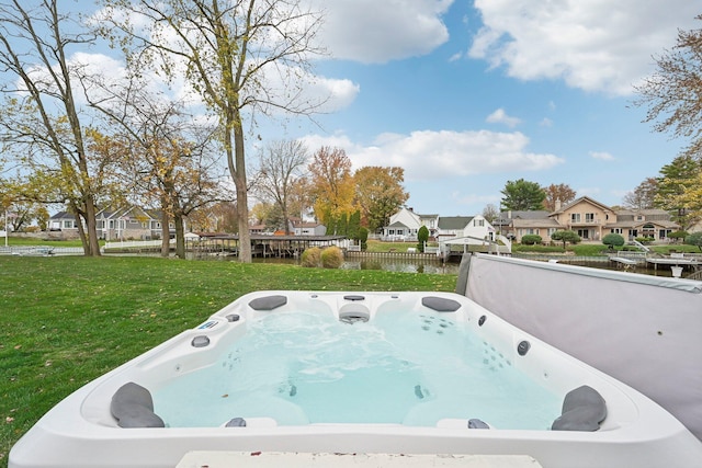 exterior space with a yard, a water view, and a hot tub