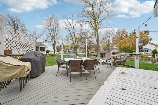 wooden terrace with area for grilling and a water view