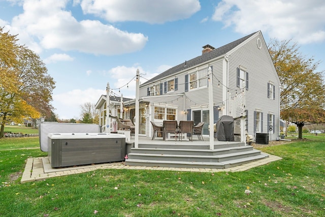 back of property with central AC, a yard, a wooden deck, and a hot tub