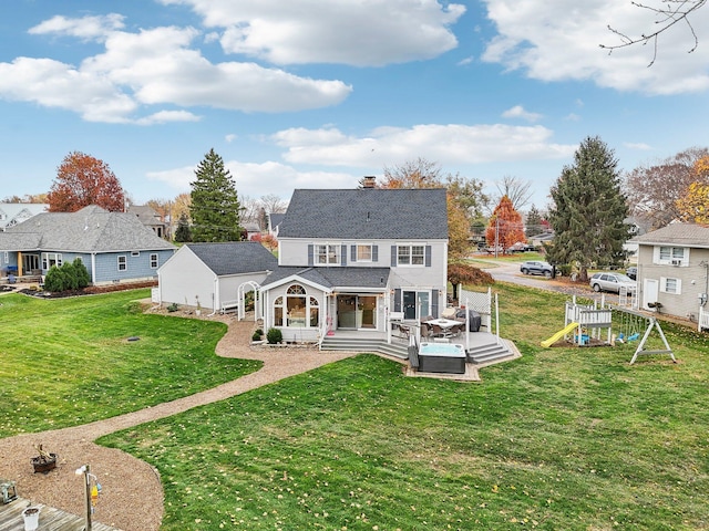 rear view of property featuring a playground, a lawn, and a deck