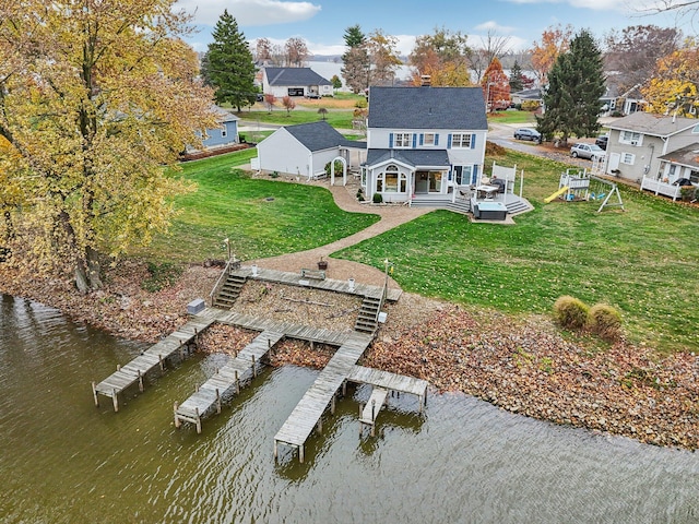 rear view of house with a playground, a lawn, a deck with water view, and a patio