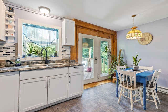 kitchen with white cabinetry, sink, french doors, hanging light fixtures, and backsplash