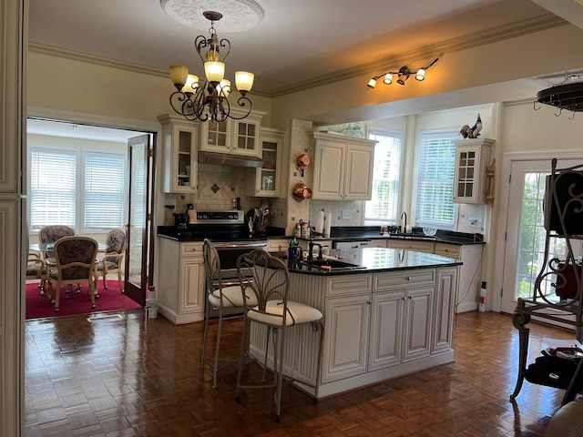 kitchen featuring stainless steel electric range oven, sink, tasteful backsplash, decorative light fixtures, and a kitchen island