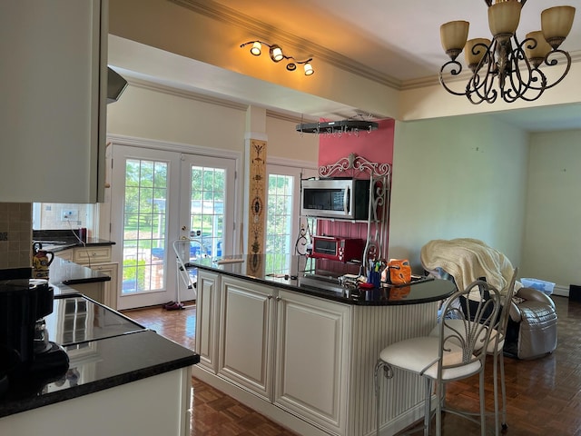 kitchen with white cabinetry, french doors, backsplash, a chandelier, and ornamental molding