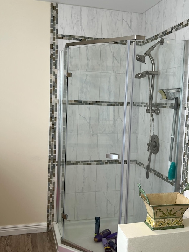 bathroom with hardwood / wood-style flooring and a shower with shower door