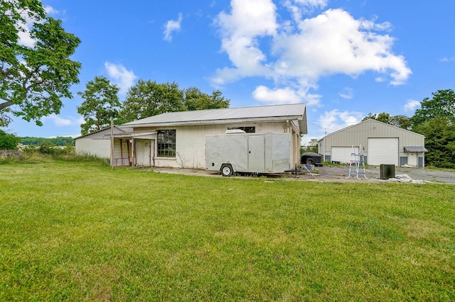 back of property featuring a yard, an outbuilding, and a garage