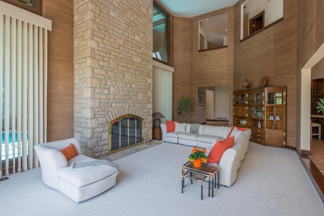 living room with carpet flooring, a towering ceiling, and a stone fireplace