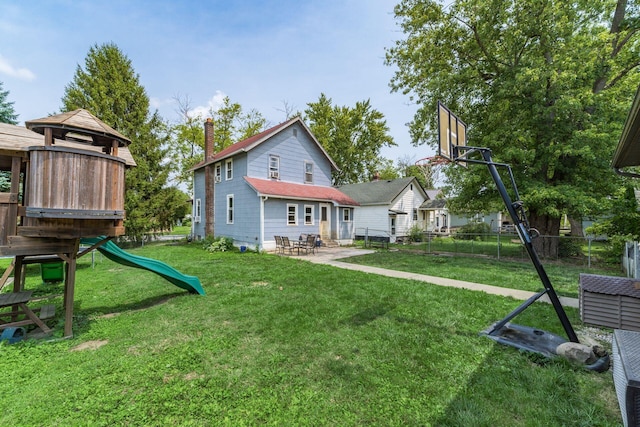 back of house featuring a yard and a playground