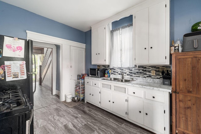 kitchen featuring backsplash, range, white cabinets, sink, and wood-type flooring