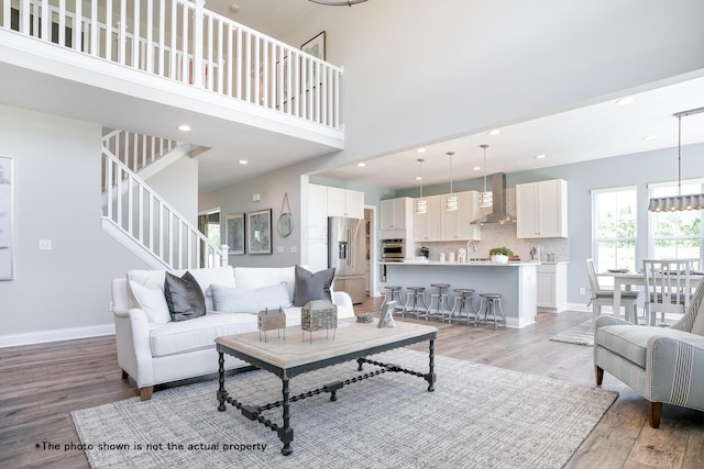 living room with a towering ceiling and light hardwood / wood-style flooring