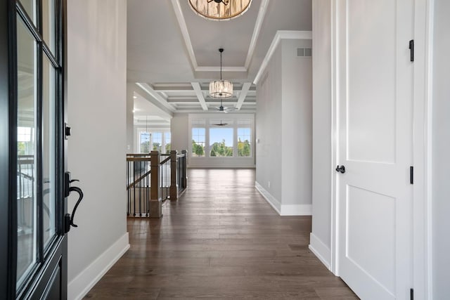 hallway featuring dark wood-type flooring, coffered ceiling, an inviting chandelier, beamed ceiling, and ornamental molding