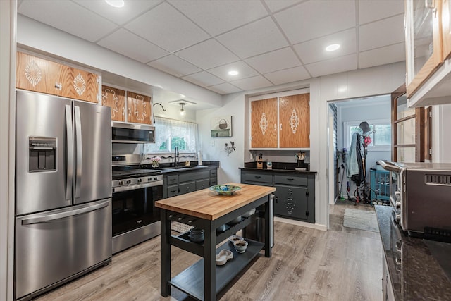 kitchen with a paneled ceiling, sink, stainless steel appliances, and light hardwood / wood-style floors