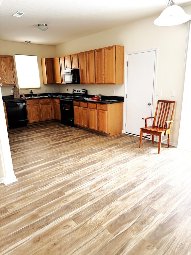 kitchen with sink, hanging light fixtures, black appliances, and light hardwood / wood-style flooring