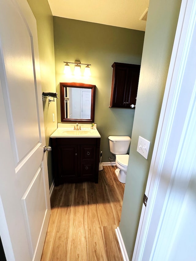 bathroom featuring hardwood / wood-style flooring, toilet, and vanity