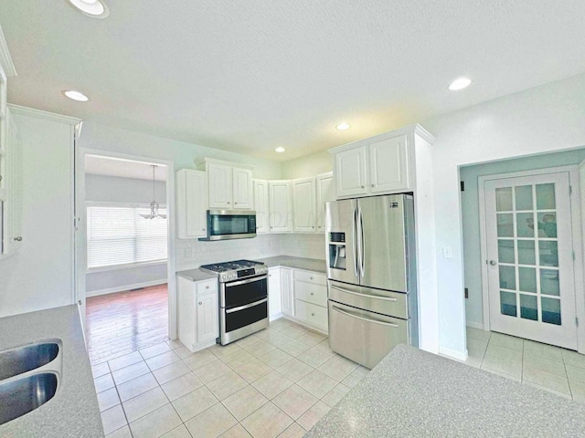 kitchen featuring white cabinets, appliances with stainless steel finishes, sink, and light tile patterned flooring