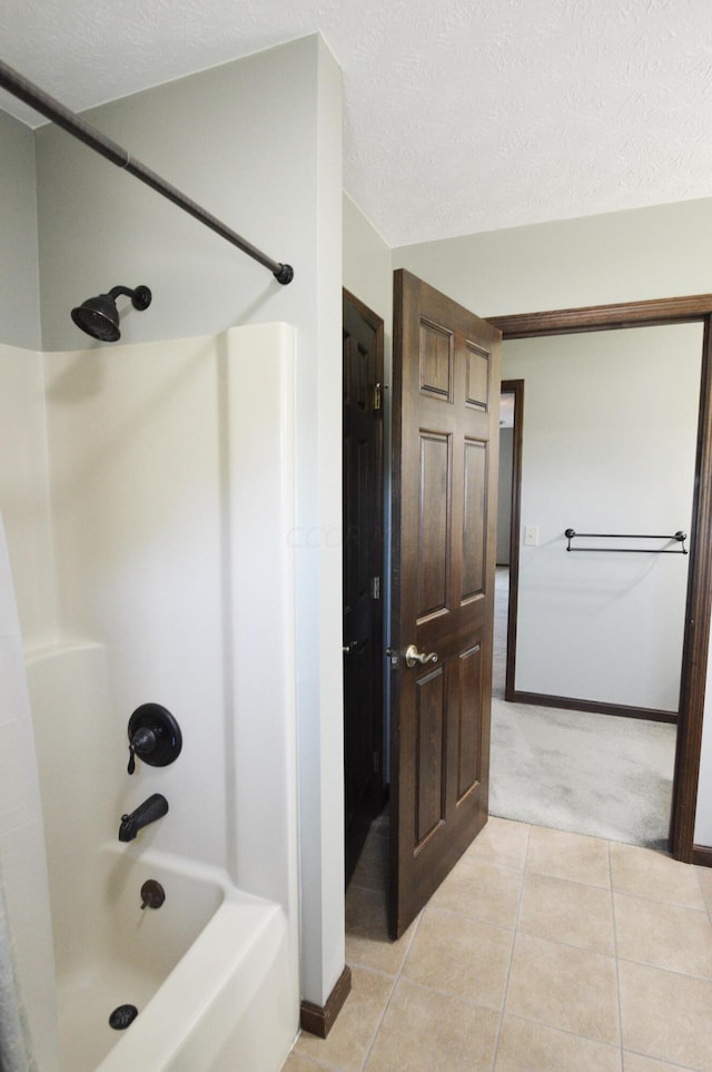 bathroom with a textured ceiling,  shower combination, and tile patterned floors