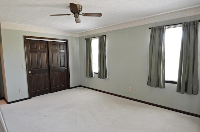 unfurnished bedroom featuring ceiling fan, light colored carpet, a closet, and multiple windows