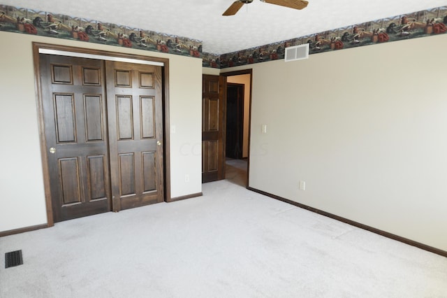 unfurnished bedroom featuring light colored carpet, ceiling fan, a textured ceiling, and a closet