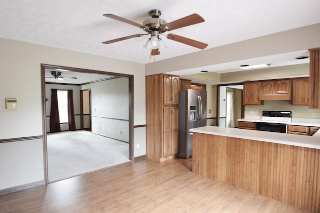 kitchen with stainless steel fridge with ice dispenser, range with electric cooktop, kitchen peninsula, ceiling fan, and light hardwood / wood-style flooring