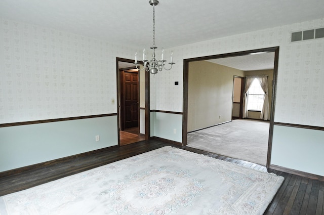 unfurnished room featuring a chandelier and dark hardwood / wood-style floors