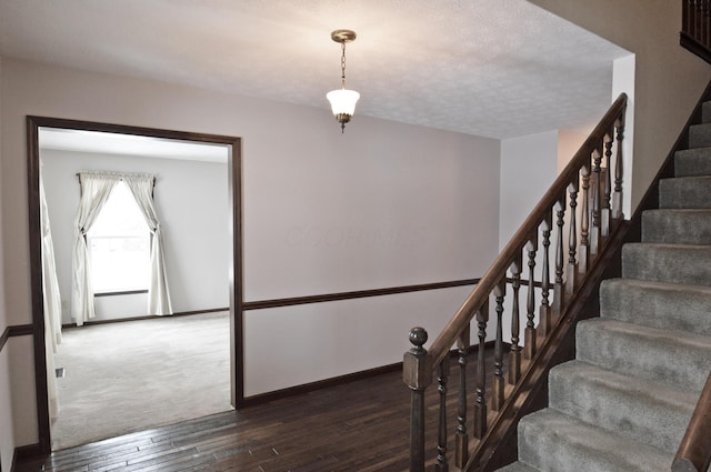 staircase with a textured ceiling and hardwood / wood-style floors