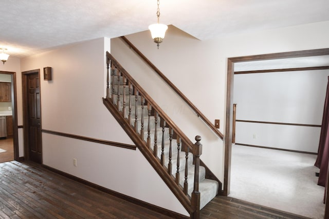 staircase with wood-type flooring and a textured ceiling