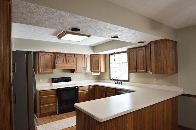 kitchen with kitchen peninsula, range with electric stovetop, stainless steel fridge, and sink