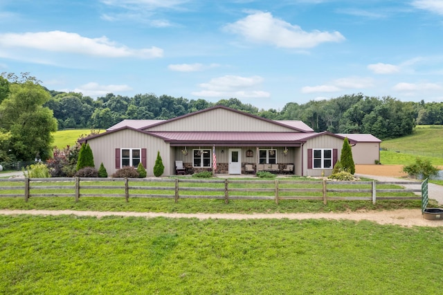 ranch-style home featuring covered porch, metal roof, a rural view, and a front yard