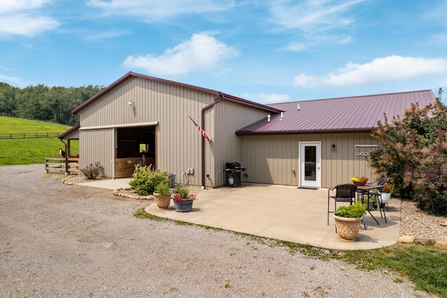 back of house featuring metal roof, an outdoor structure, and a patio