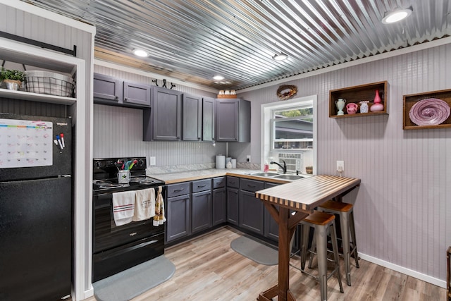 kitchen featuring open shelves, a sink, light wood-style floors, gray cabinets, and black appliances