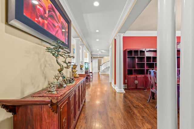 hallway featuring dark hardwood / wood-style floors, ornate columns, and ornamental molding