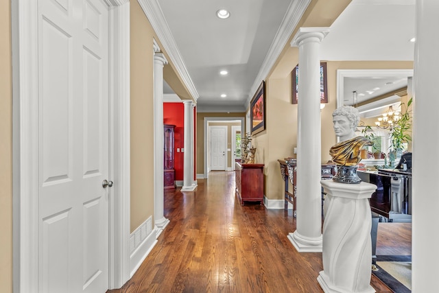 hallway featuring dark hardwood / wood-style floors, decorative columns, ornamental molding, and a notable chandelier