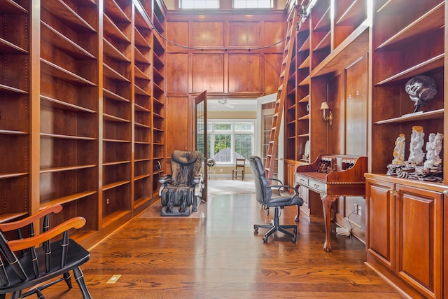 home office featuring hardwood / wood-style floors, built in shelves, and wooden walls