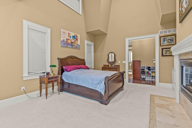 bedroom featuring carpet, a towering ceiling, and a tile fireplace