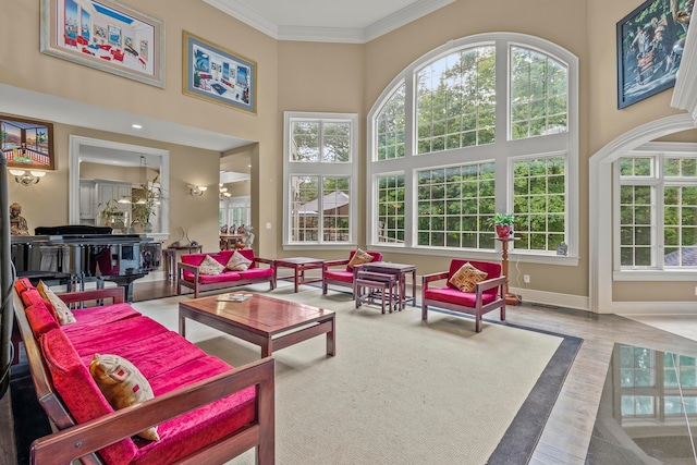 living room featuring a high ceiling, light wood-type flooring, and ornamental molding