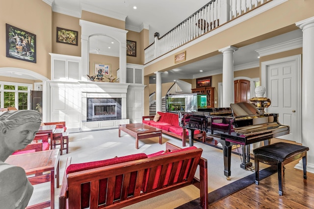 living room with ornate columns, crown molding, hardwood / wood-style floors, and a towering ceiling