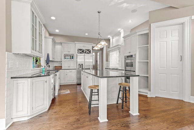 kitchen featuring decorative backsplash, dark wood-type flooring, built in appliances, white cabinets, and a kitchen island