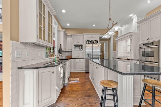 kitchen with white cabinets, dark hardwood / wood-style flooring, stainless steel appliances, and a breakfast bar area