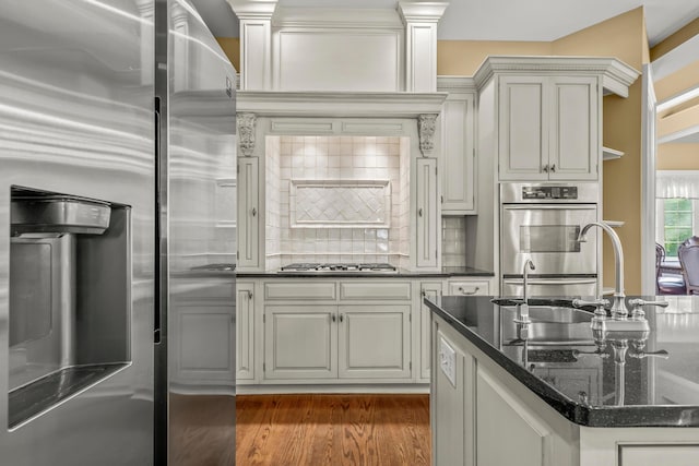 kitchen featuring backsplash, sink, dark hardwood / wood-style floors, dark stone countertops, and appliances with stainless steel finishes