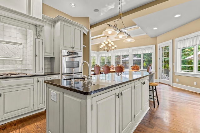 kitchen with backsplash, dark hardwood / wood-style flooring, plenty of natural light, and an island with sink