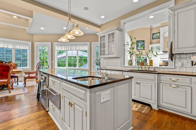 kitchen featuring backsplash, a center island with sink, white cabinets, sink, and wood-type flooring