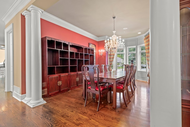 dining area with decorative columns, crown molding, a notable chandelier, and hardwood / wood-style flooring