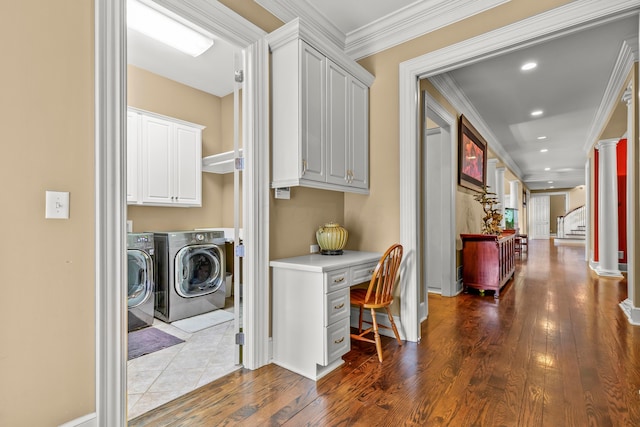 clothes washing area with cabinets, hardwood / wood-style flooring, independent washer and dryer, ornamental molding, and ornate columns