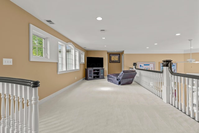 living area with ceiling fan, light colored carpet, and ornamental molding