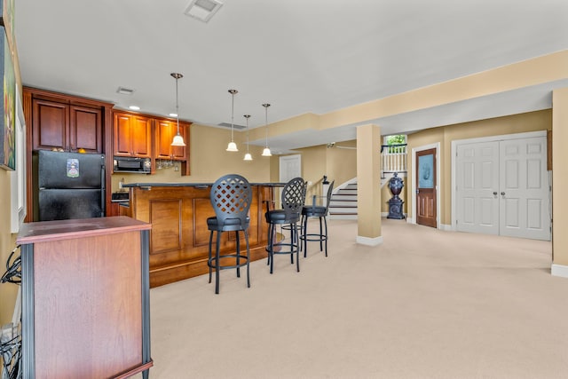 kitchen featuring pendant lighting, light colored carpet, a kitchen breakfast bar, and black appliances