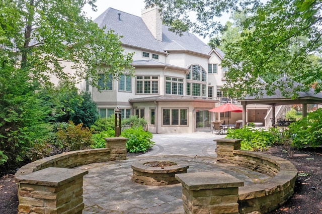 back of property featuring a gazebo, a patio area, and a fire pit