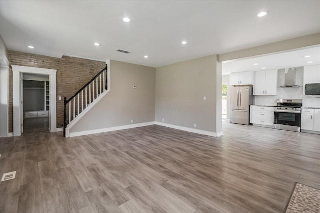 unfurnished living room featuring light wood-type flooring and brick wall